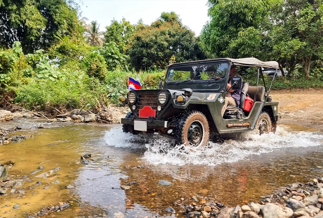 Off-road jeep crossing a shallow stream during countryside adventure near Angkor Wat, Cambodia